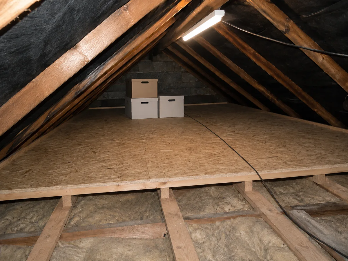 The same loft after work: boarded deck raised over 270mm insulation, LED batten light and stacked storage boxes