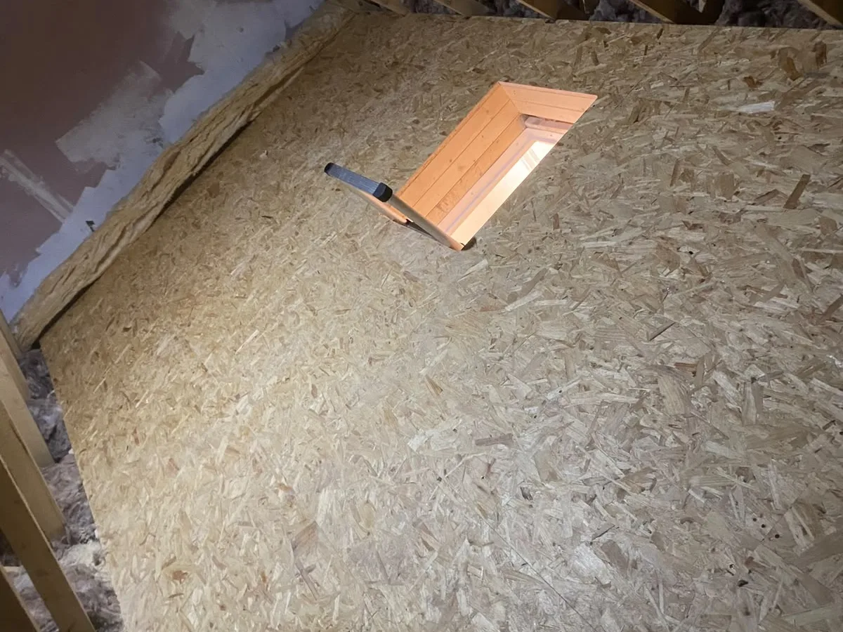 Boarded loft deck with light coming up through the open hatch