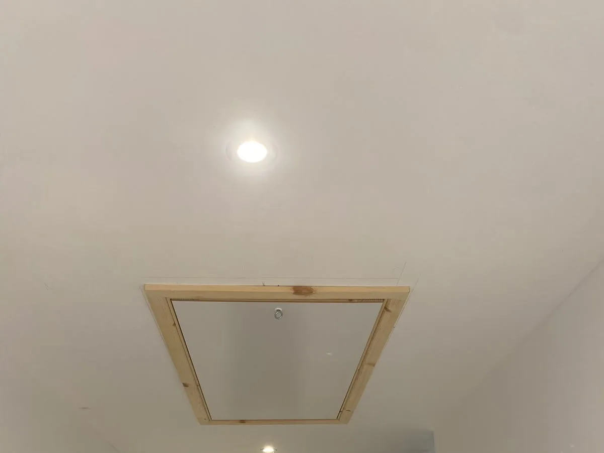 Closed loft hatch set into a modern hallway ceiling