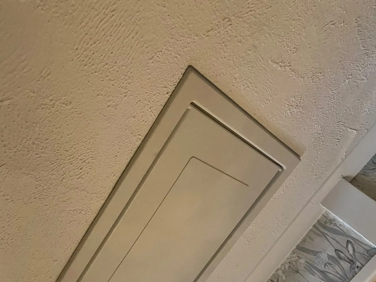 Painted loft hatch sitting flush in an older ceiling