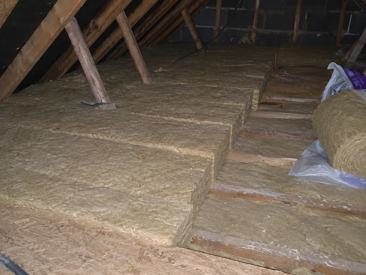 Second layer of mineral wool being laid over the joists during a 270mm insulation top-up