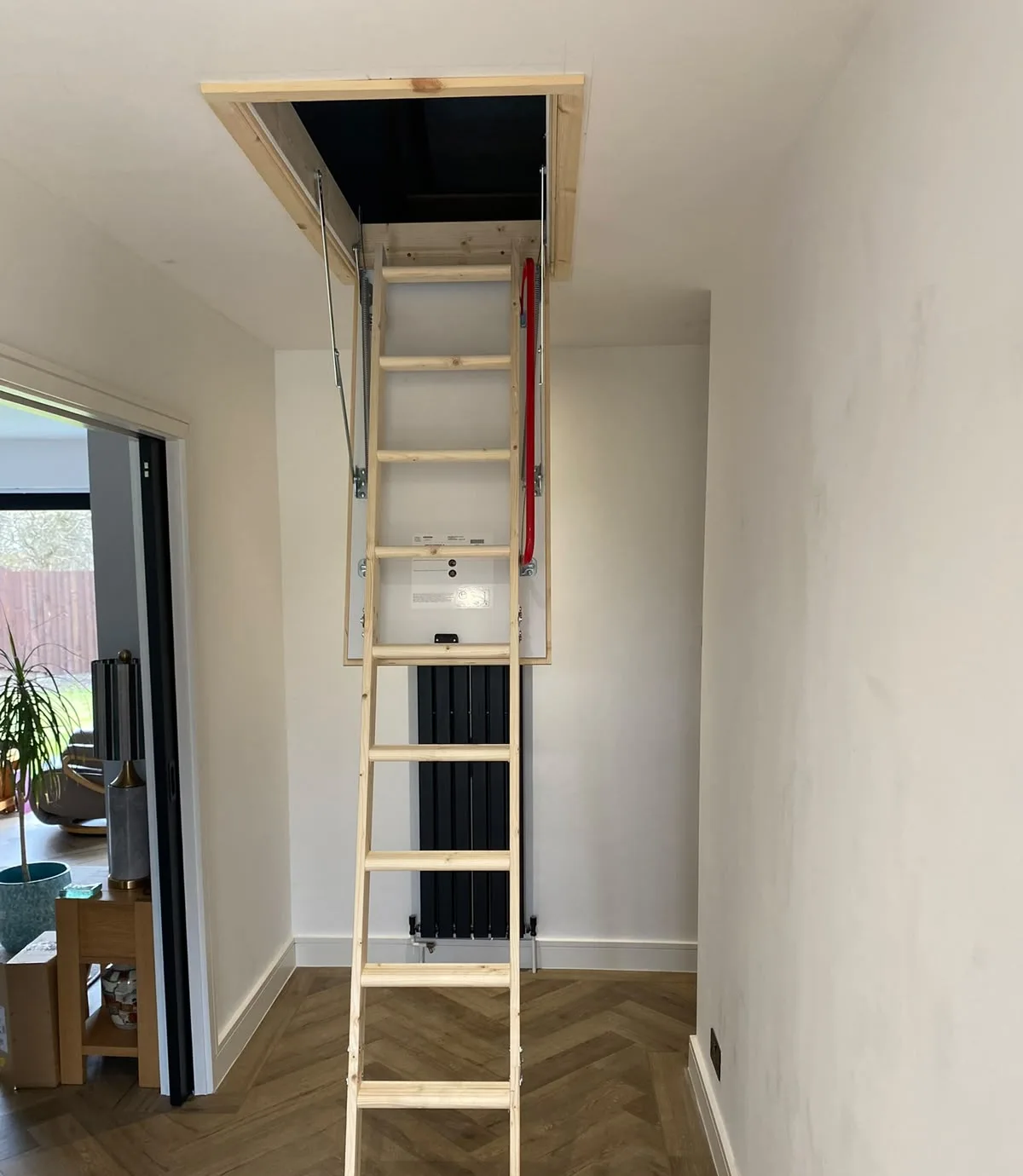 Timber folding loft ladder extended down into a hallway, hatch open above