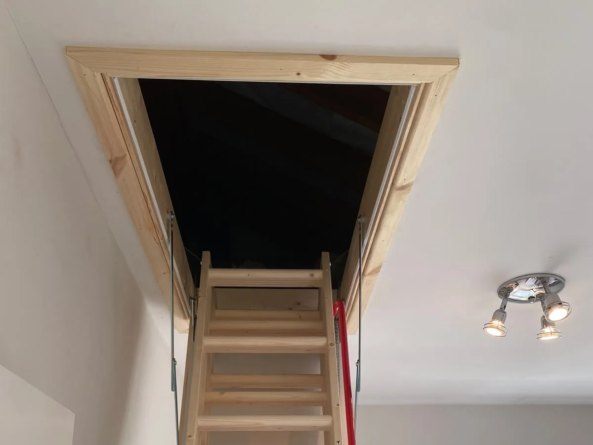 Timber folding loft ladder extended down into a bright landing