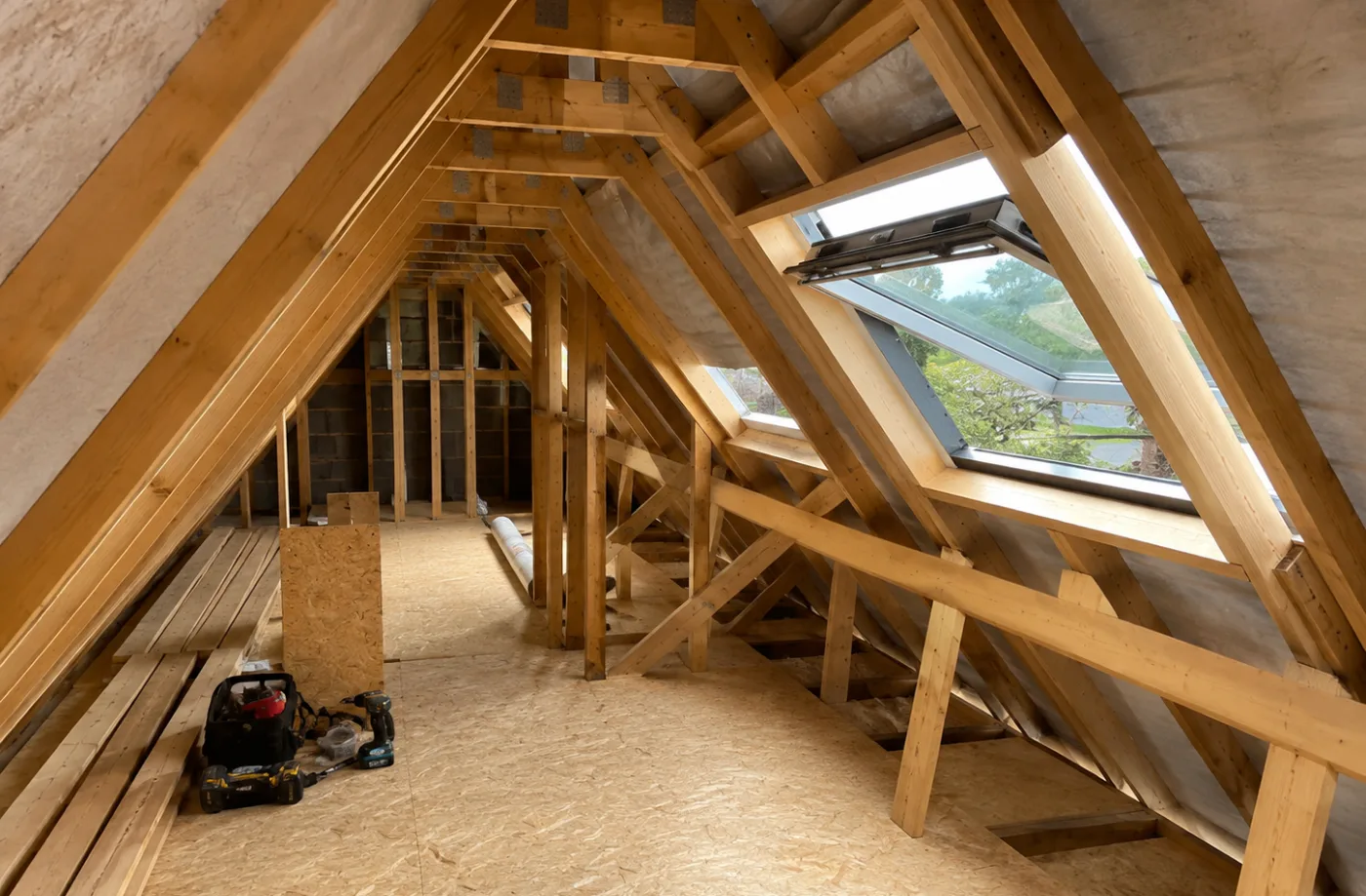 Loft roof space with twin roof windows letting daylight in over a boarded deck