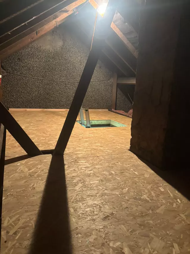 Boarded loft floor with the hatch at the far end, lit by a single bulb