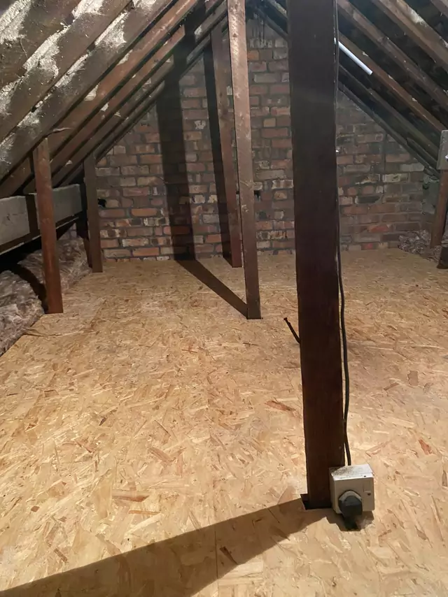 Boarded loft running up to an exposed brick gable, timber prop in the foreground