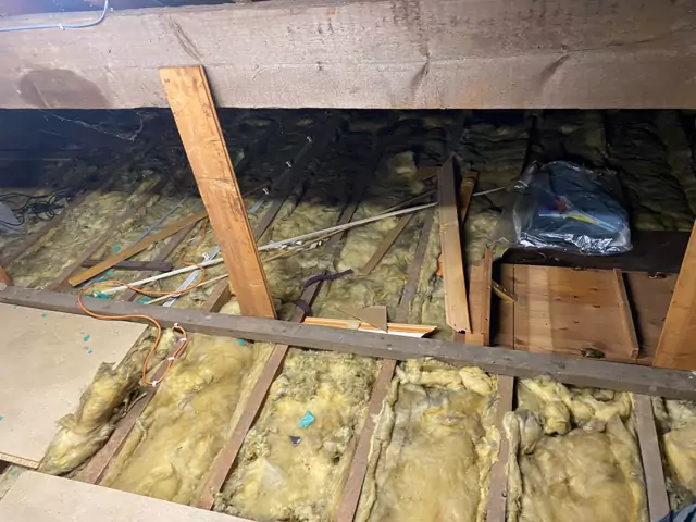 Before: uneven insulation and loose boards across the ceiling joists