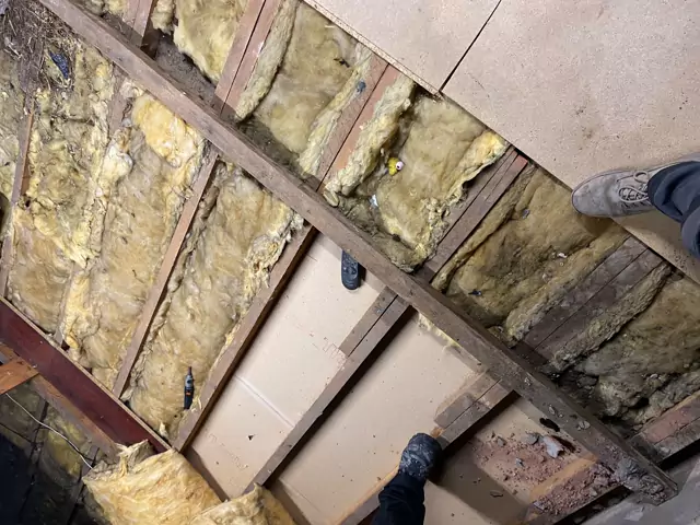 Before: old boards lifted to show worn insulation between the joists