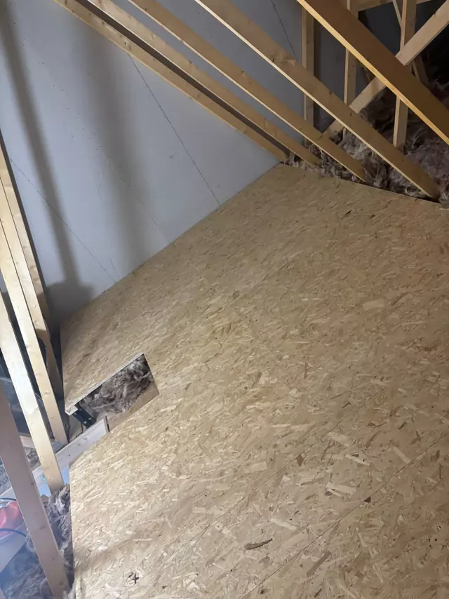 Boarding cut round a chimney breast in a trussed loft