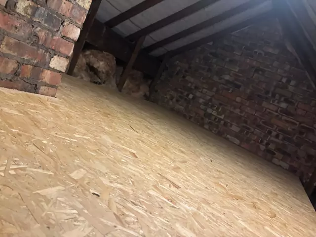 Boarded floor running up to a brick chimney and party wall