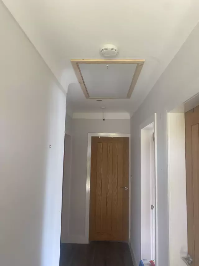 Hatch with timber trim in a long hallway ceiling